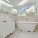 Elegant minimalist bathroom featuring a white bathtub and sleek fixtures.